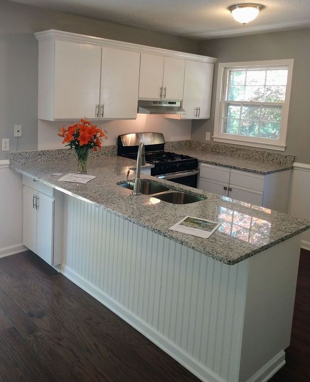 A kitchen with granite counter tops and white cabinets