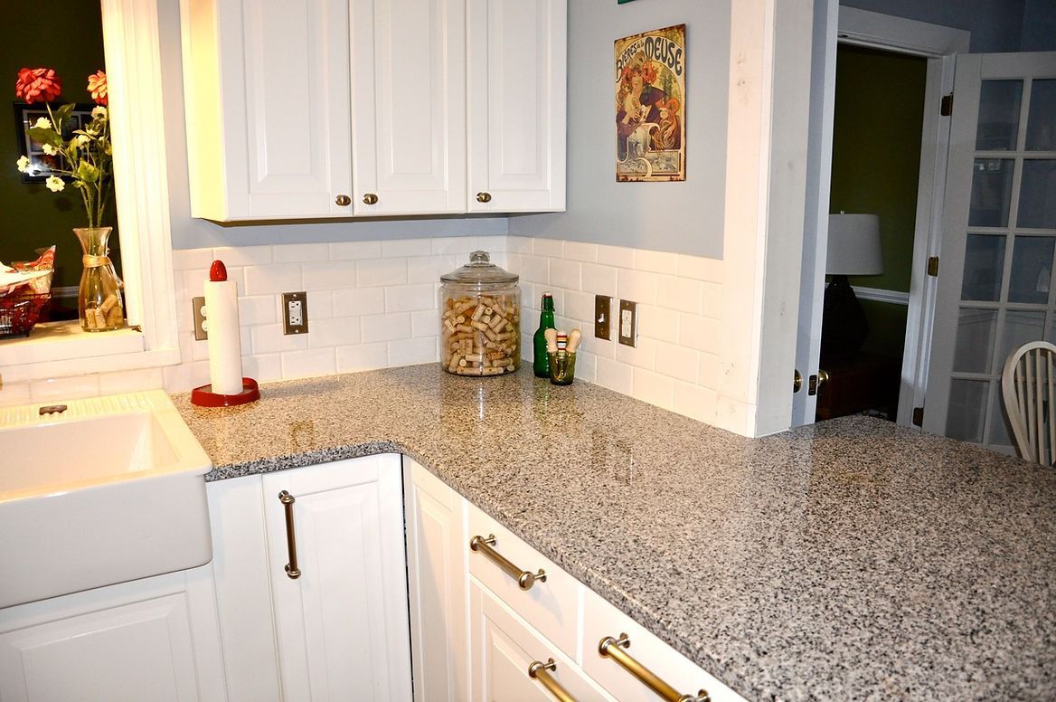 A kitchen with white cabinets and granite counter tops.