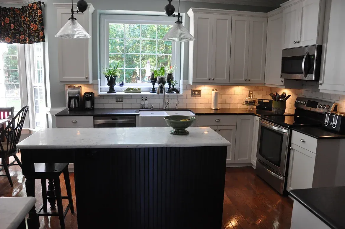 A kitchen with white cabinets and black counter tops