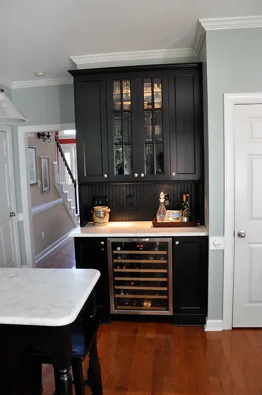 A kitchen with black cabinets and a wine cooler.