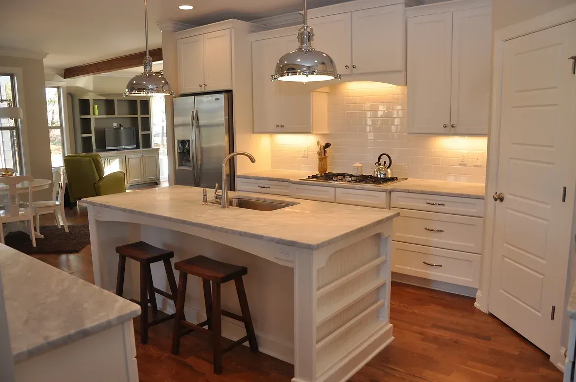 A kitchen with white cabinets and stools and a large island