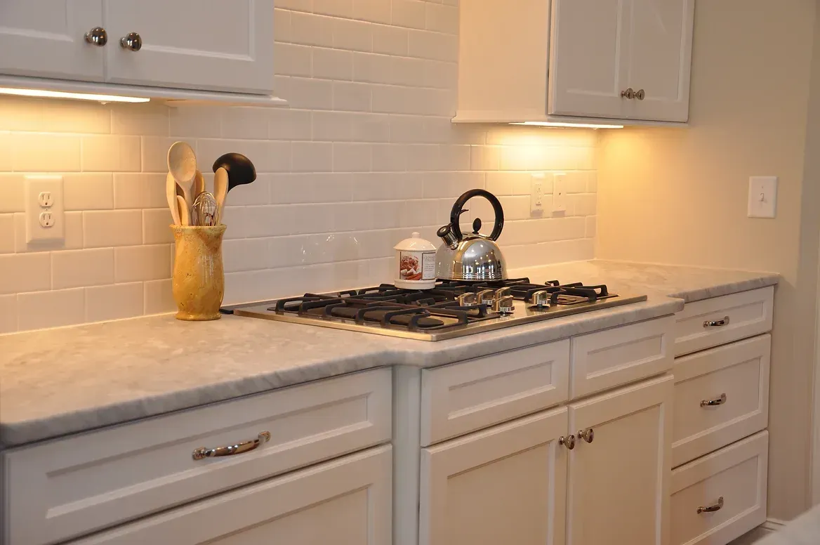 A kitchen with white cabinets and a stove top oven.