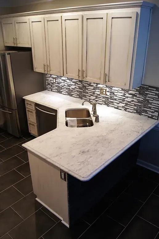 A kitchen with white cabinets , a sink , and a refrigerator.