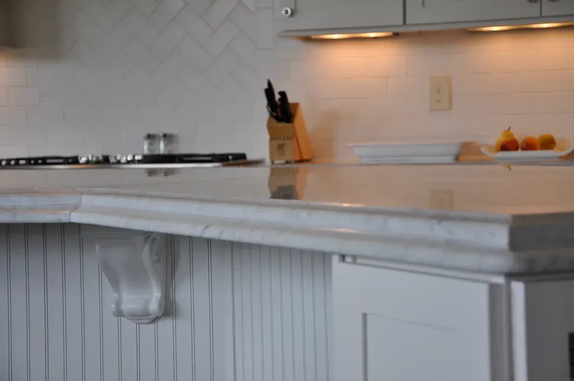 A kitchen with white cabinets and a marble counter top