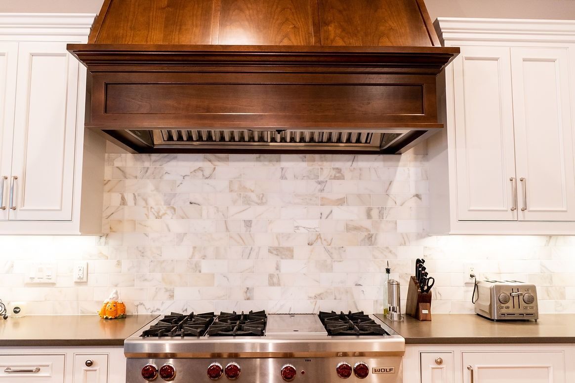 A kitchen with a stove top oven and a wooden hood above it.