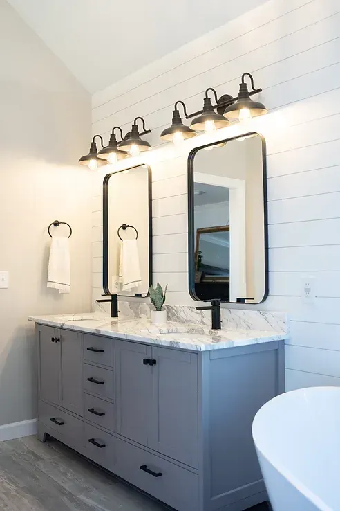 A bathroom with two sinks , two mirrors , and a bathtub.