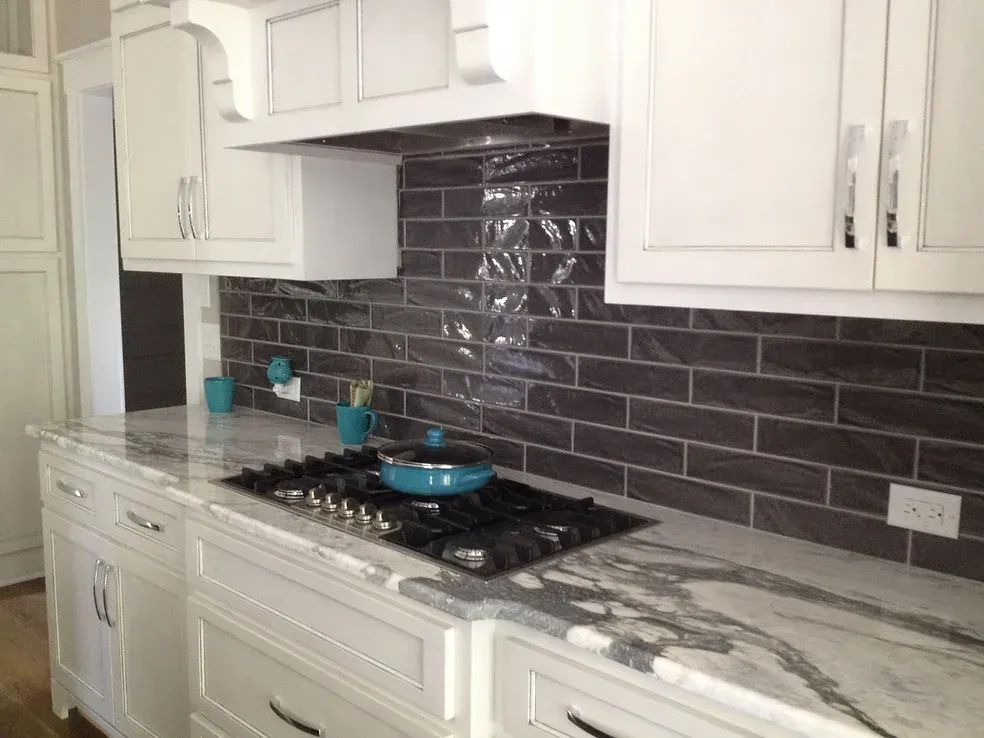 A kitchen with white cabinets and a stove top oven with a pan on it.