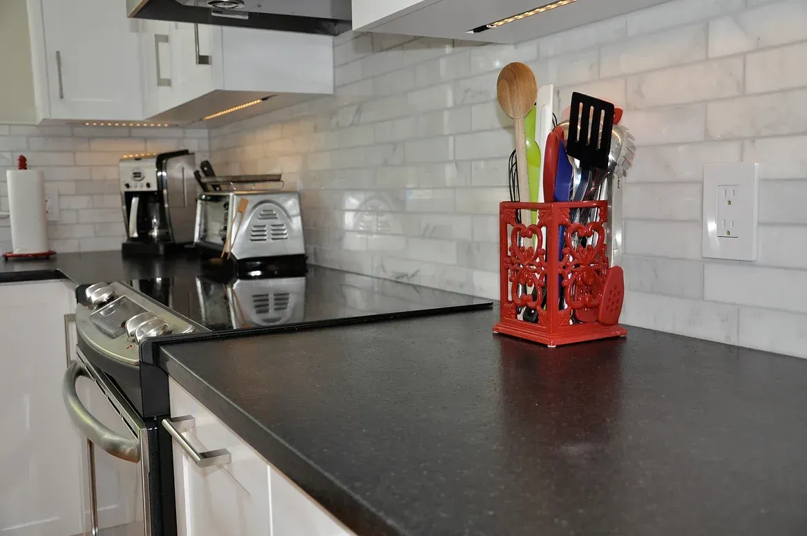 A kitchen counter with a red utensil holder on it
