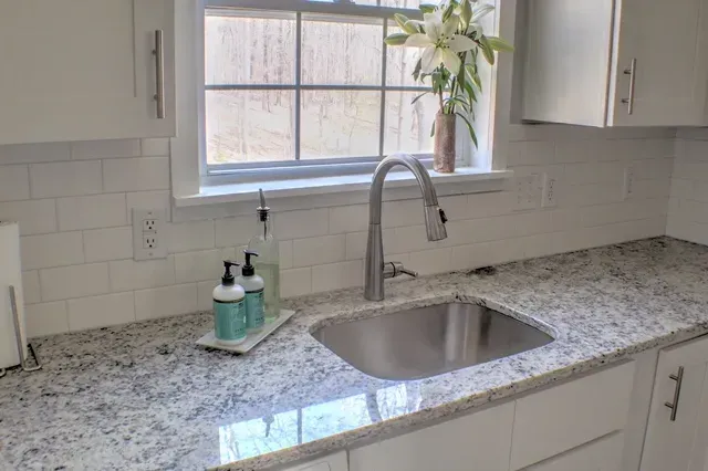 A kitchen with granite counter tops and a stainless steel sink.