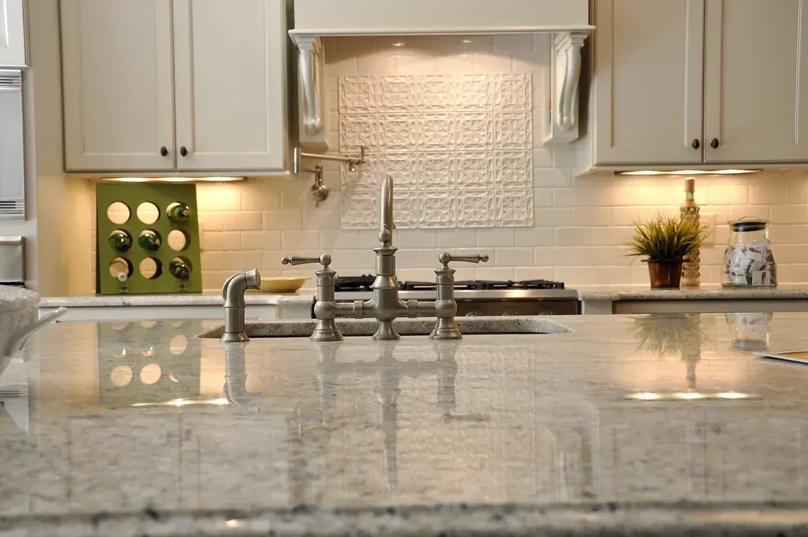 A kitchen with white cabinets , granite counter tops , a sink and a stove.