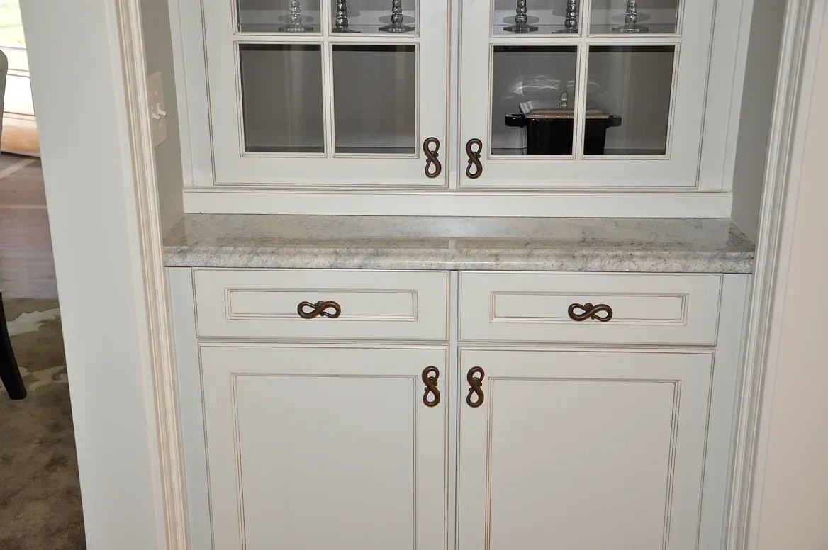 A white cabinet with glass doors and drawers in a kitchen.