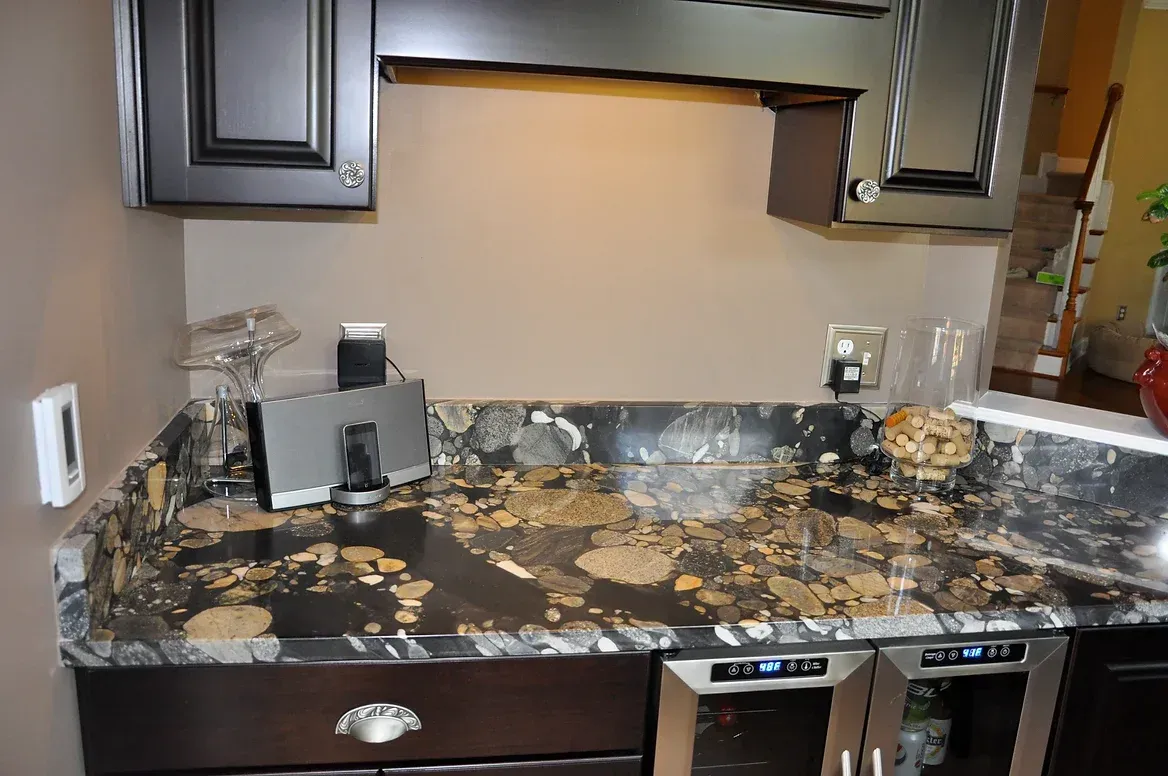 A kitchen with a granite counter top and a wine cooler