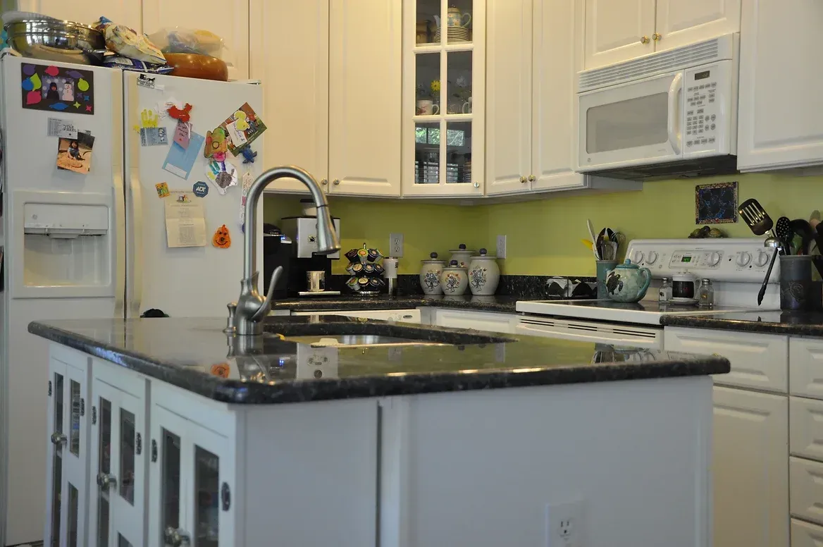 A kitchen with white cabinets and black counter tops