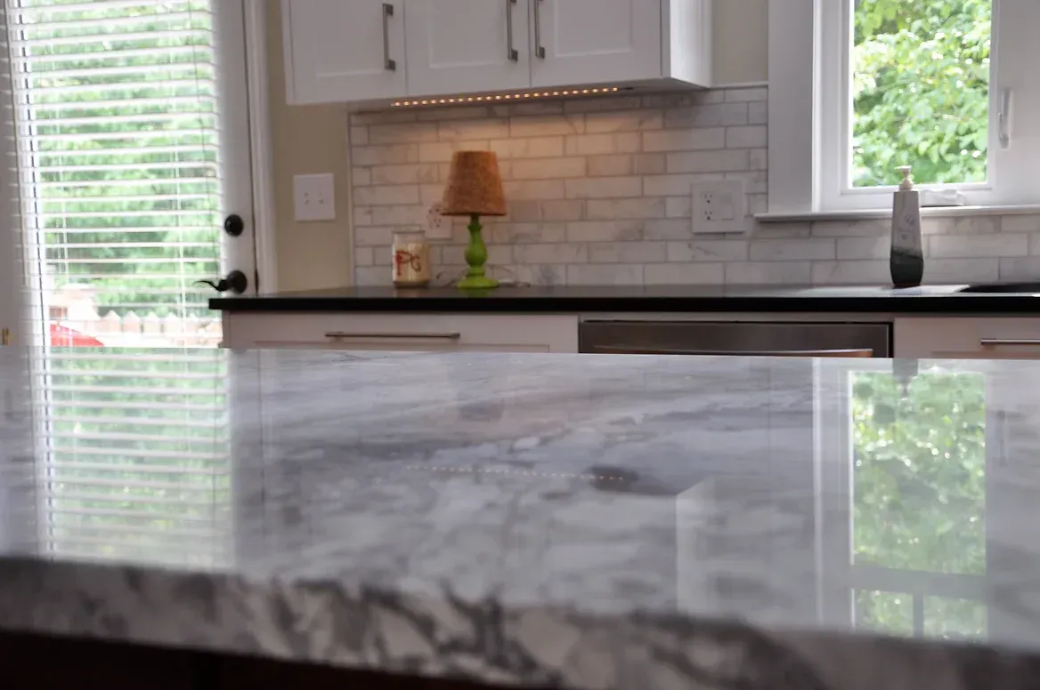 A kitchen with a marble counter top and a lamp on the counter.