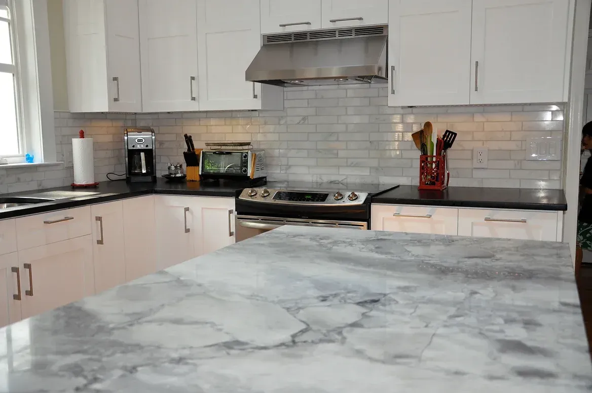 A kitchen with white cabinets and black counter tops