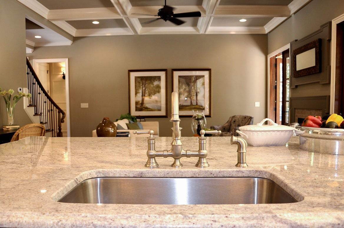 A kitchen with a stainless steel sink and a granite counter top.