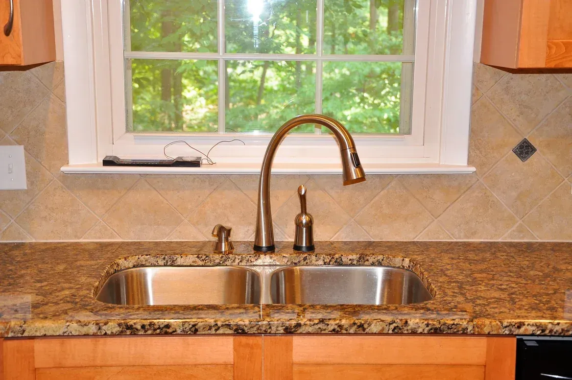A kitchen sink with a faucet and a window above it.
