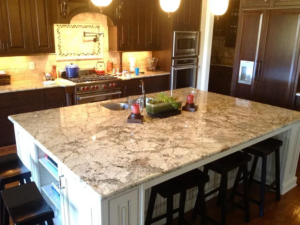 A kitchen with a large granite counter top and stools.