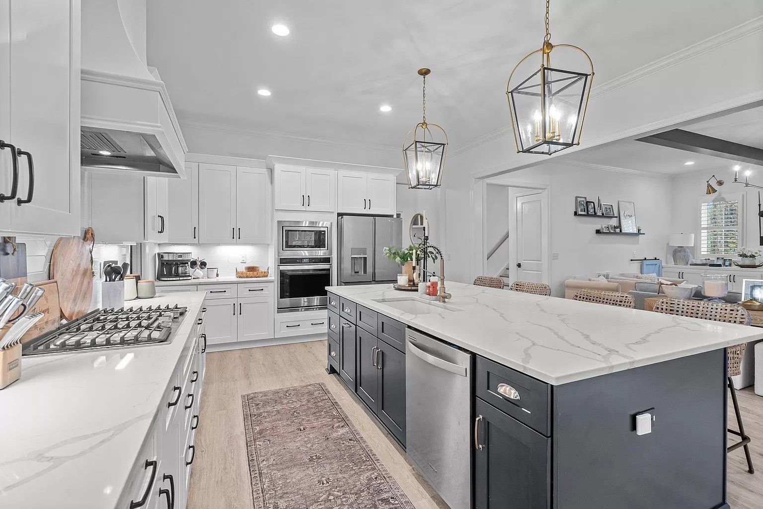 A kitchen with white cabinets , stainless steel appliances , and a large island.