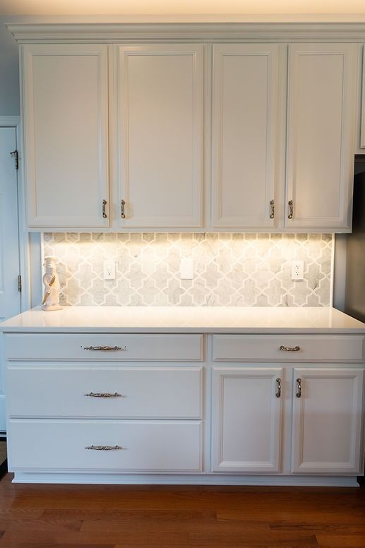A kitchen with white cabinets and a white counter top.