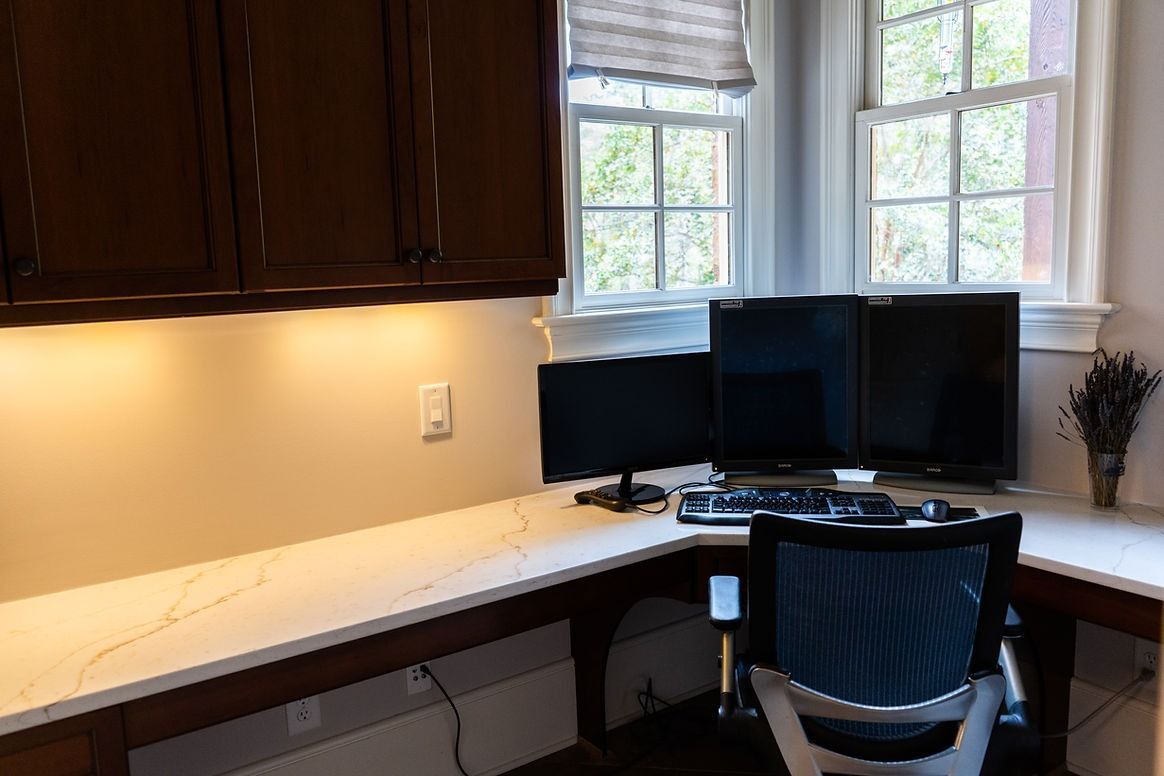 A home office with two computer monitors on a desk.