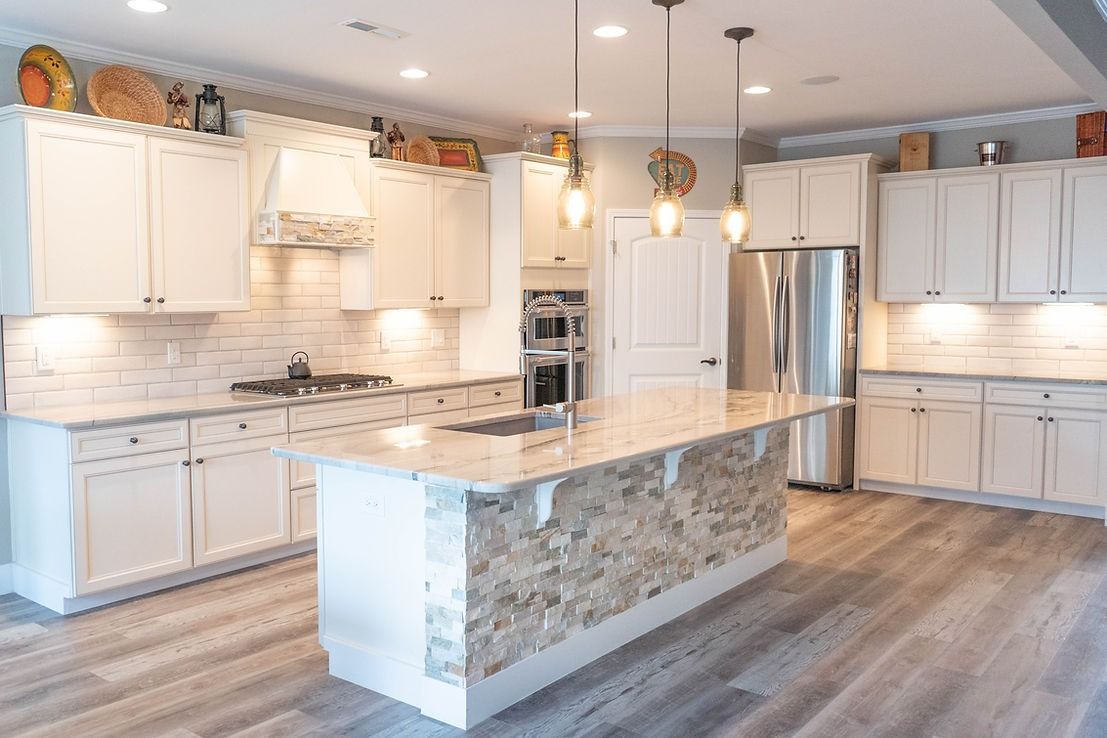 A kitchen with white cabinets , granite counter tops , stainless steel appliances and a large island.