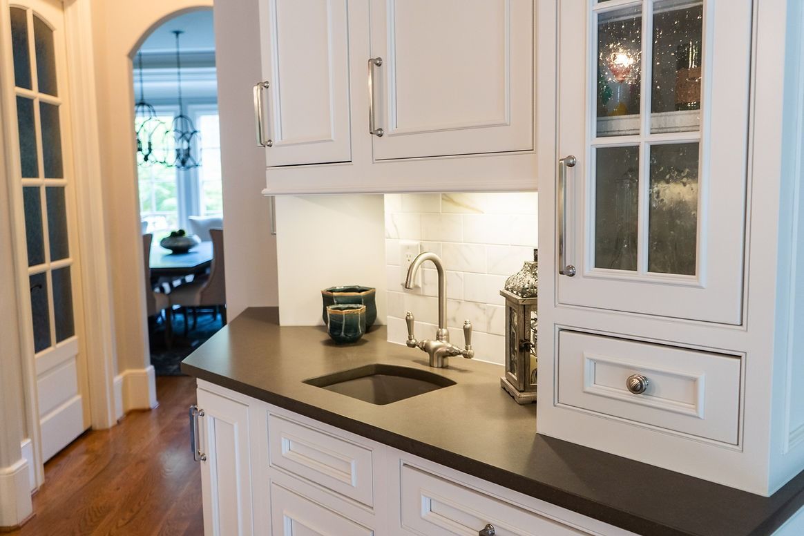 A kitchen with white cabinets , a sink and a faucet.