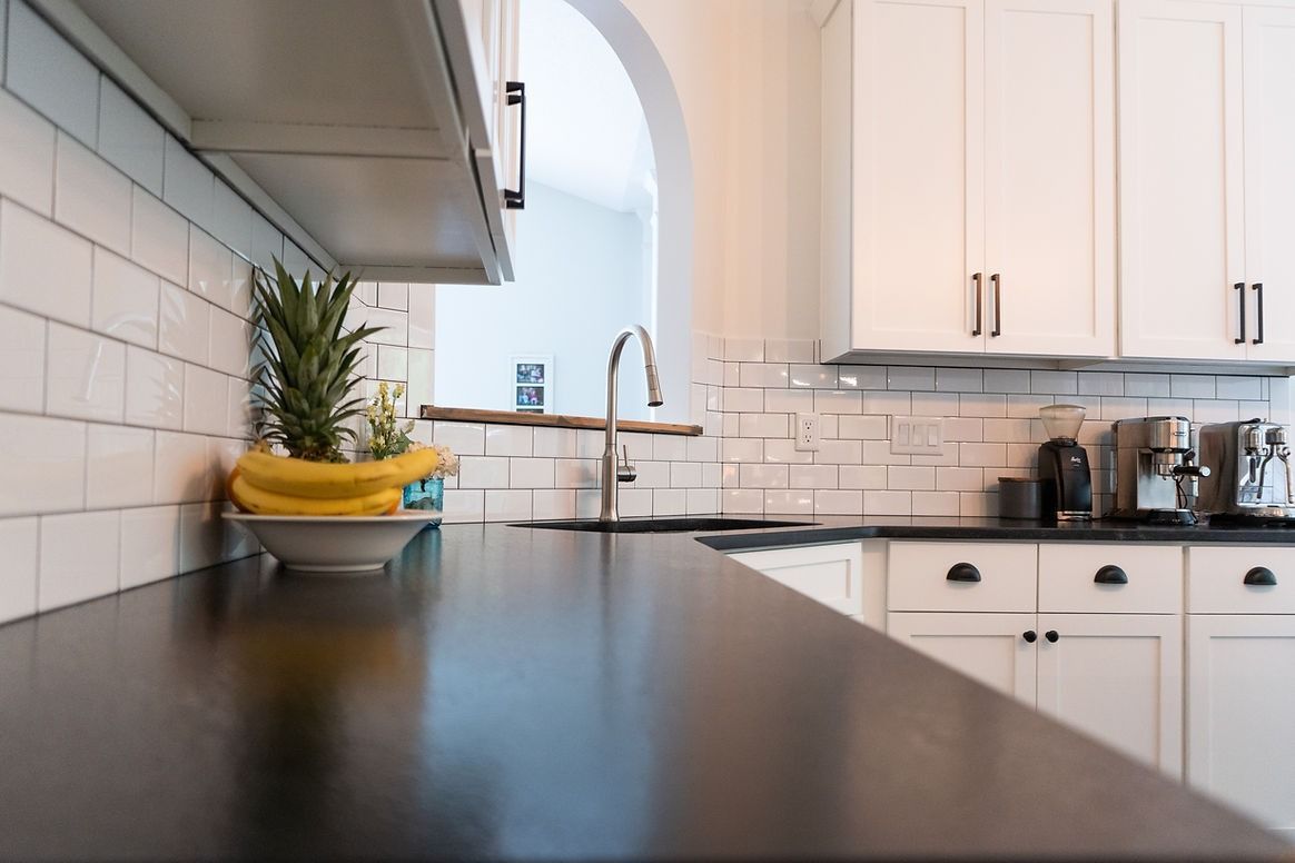 A kitchen with white cabinets and a black counter top.