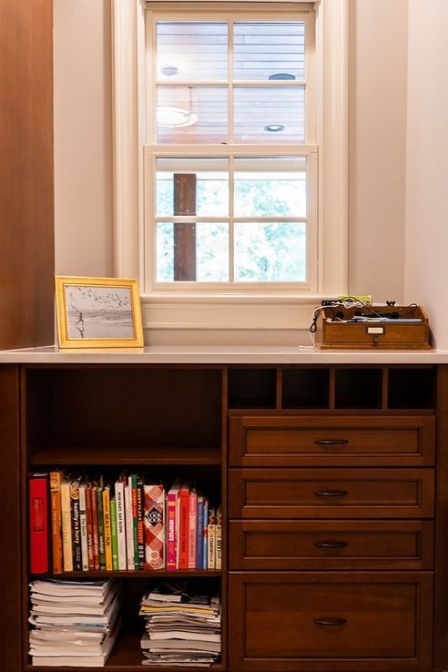 A bookshelf filled with books and a picture frame next to a window.