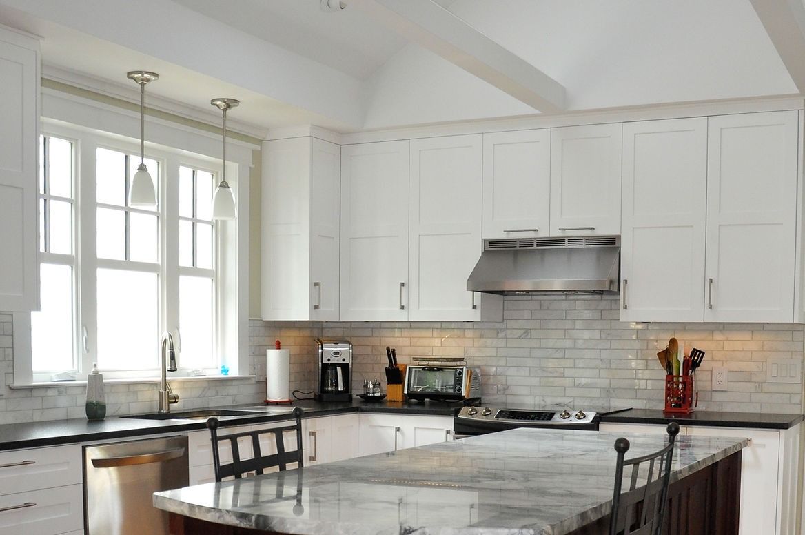A kitchen with white cabinets , granite counter tops , stainless steel appliances and a large island.