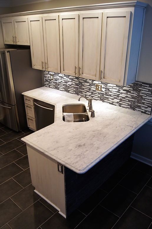 A kitchen with white cabinets , a sink , and a refrigerator.