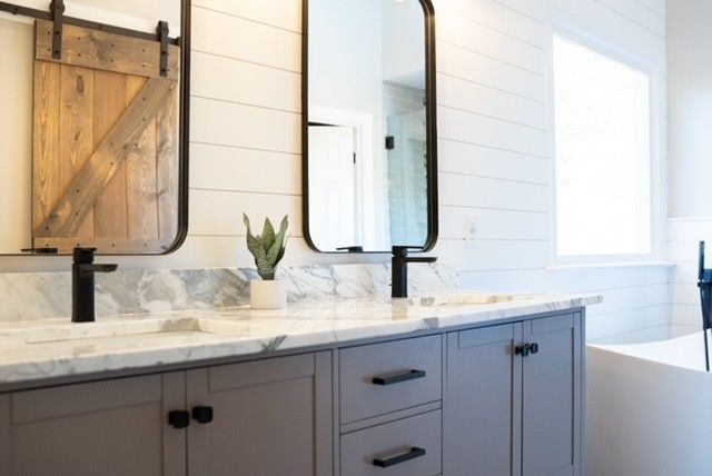A bathroom with two sinks , two mirrors and a tub.