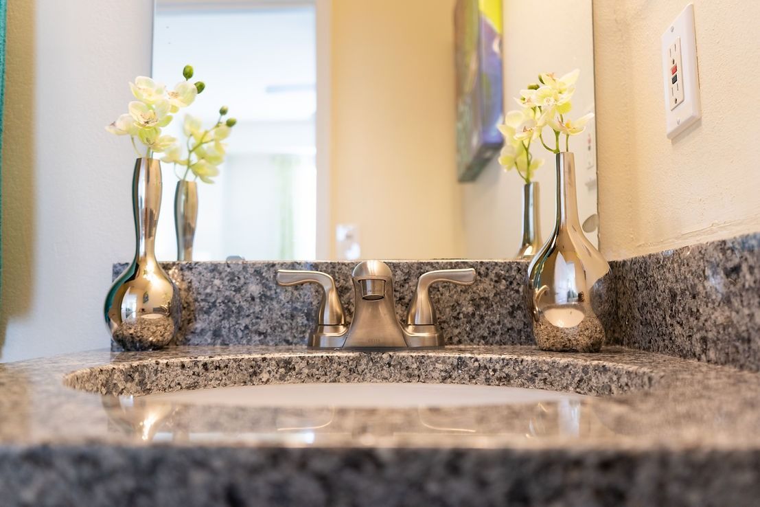 A bathroom sink with a mirror and vases on the counter.