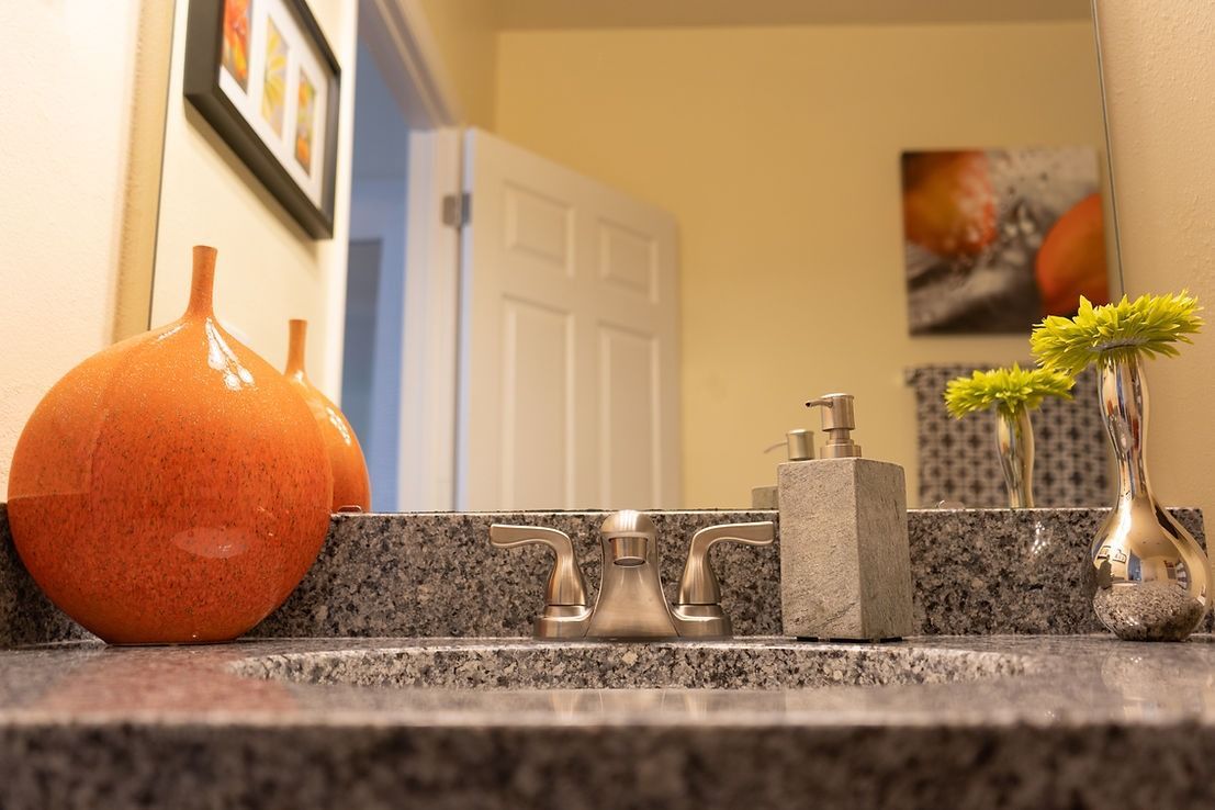 A bathroom sink with a vase on top of it and a mirror.