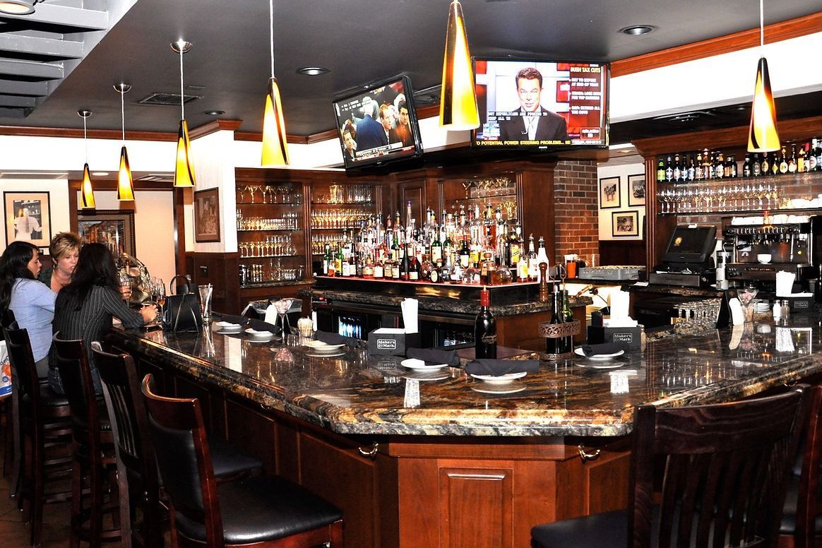 A group of people are sitting at a bar in a restaurant.