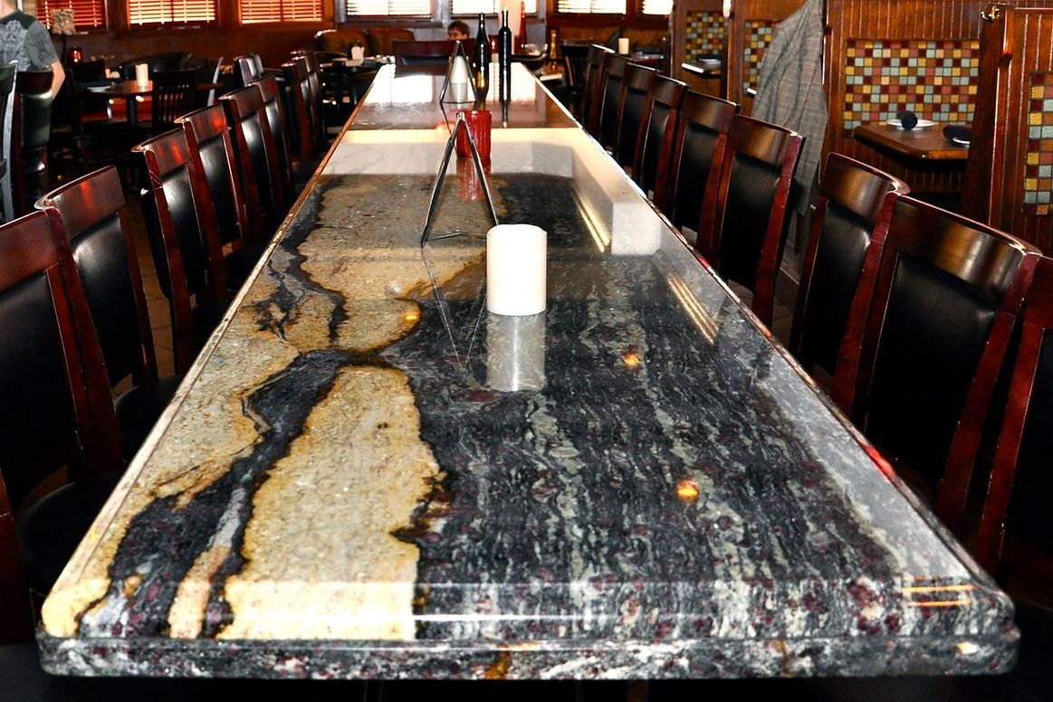 A long marble table in a restaurant with candles on it
