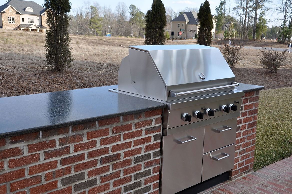 A stainless steel grill is built into a brick wall.