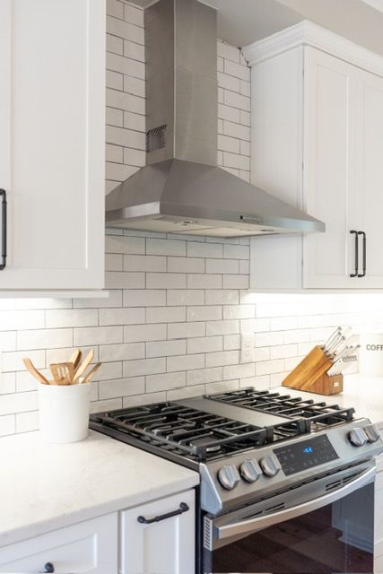 A kitchen with a stove top oven and a hood above it.
