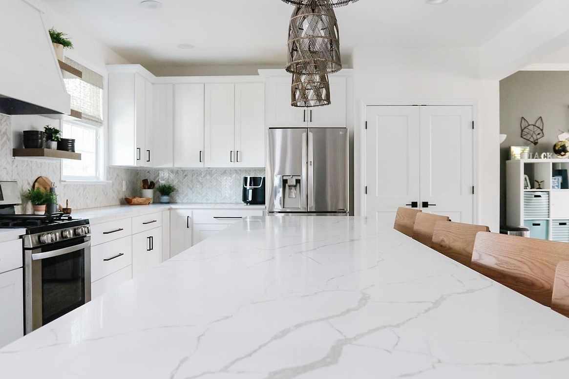 A kitchen with white cabinets , stainless steel appliances , and a marble counter top.