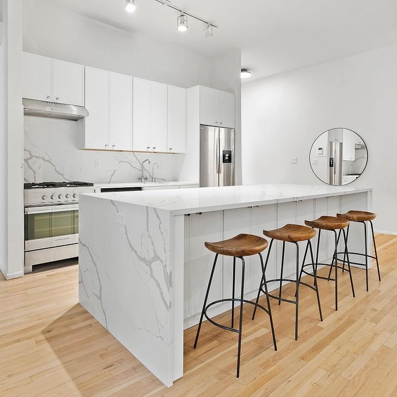A kitchen with a large island and wooden stools