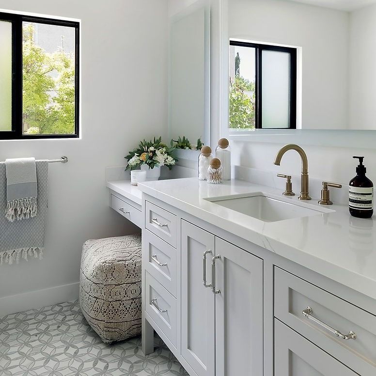 A bathroom with white cabinets a sink and a mirror
