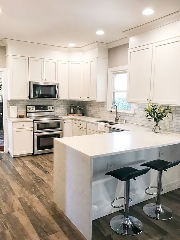 A kitchen with white cabinets , stainless steel appliances , and a large island.