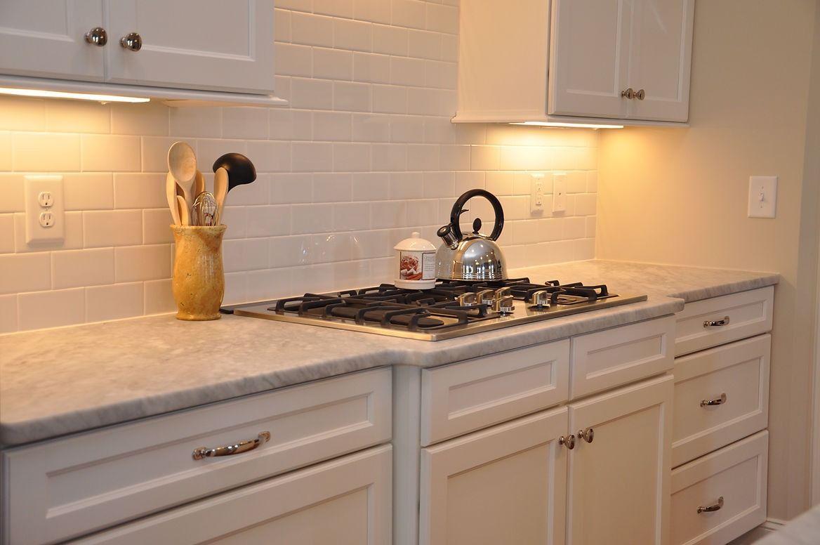 A kitchen with white cabinets and a stove top oven