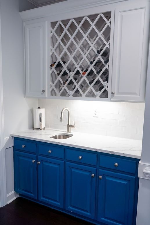 A kitchen with blue cabinets and a wine rack above the sink.