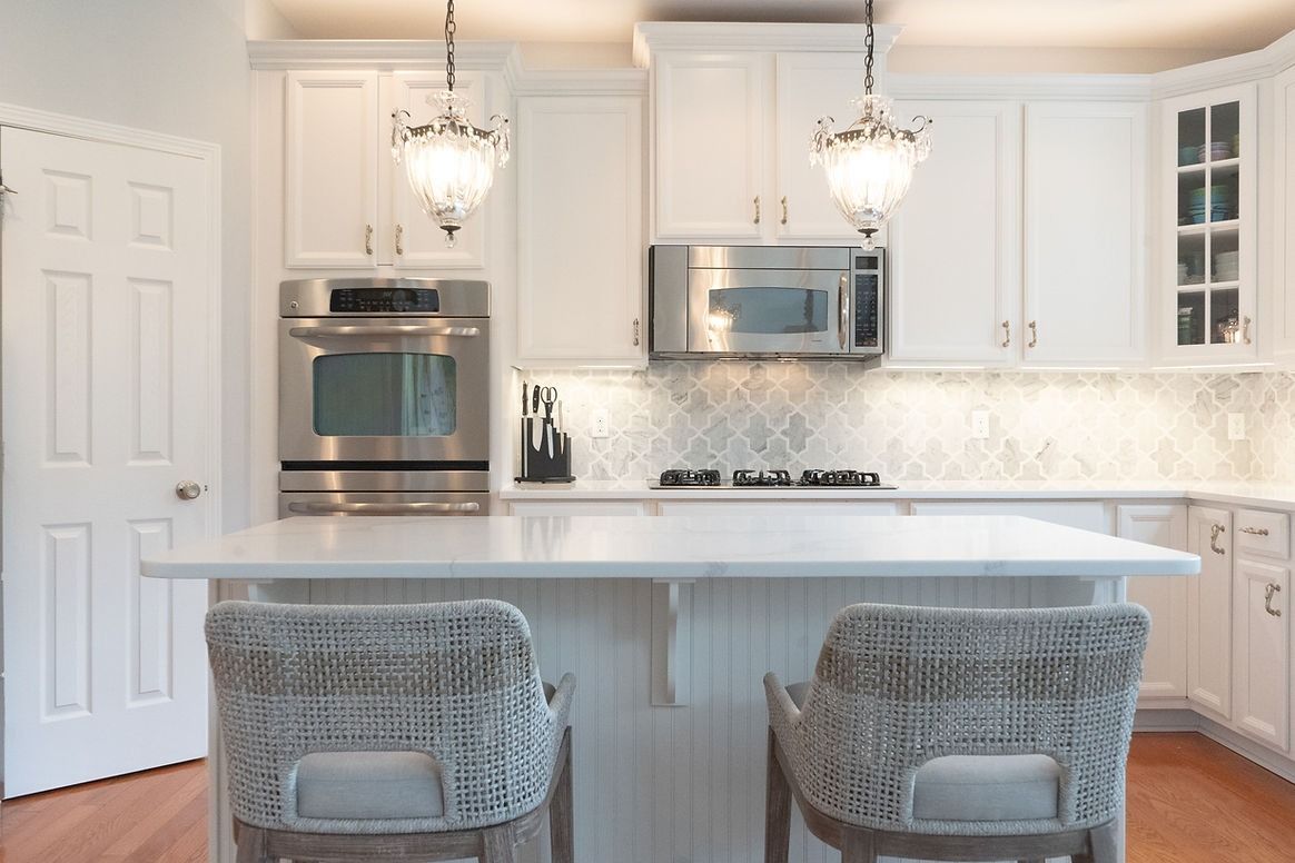 A kitchen with white cabinets , stainless steel appliances , and a large island.