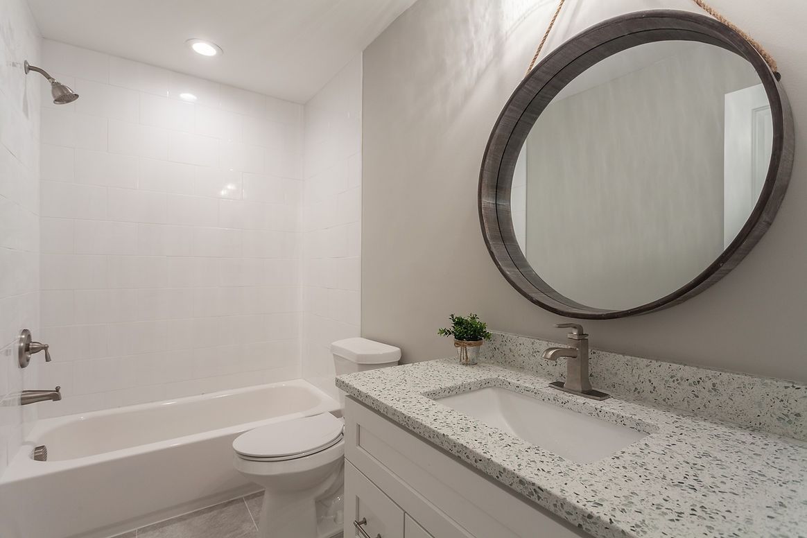 A bathroom with a sink , toilet , bathtub and mirror.