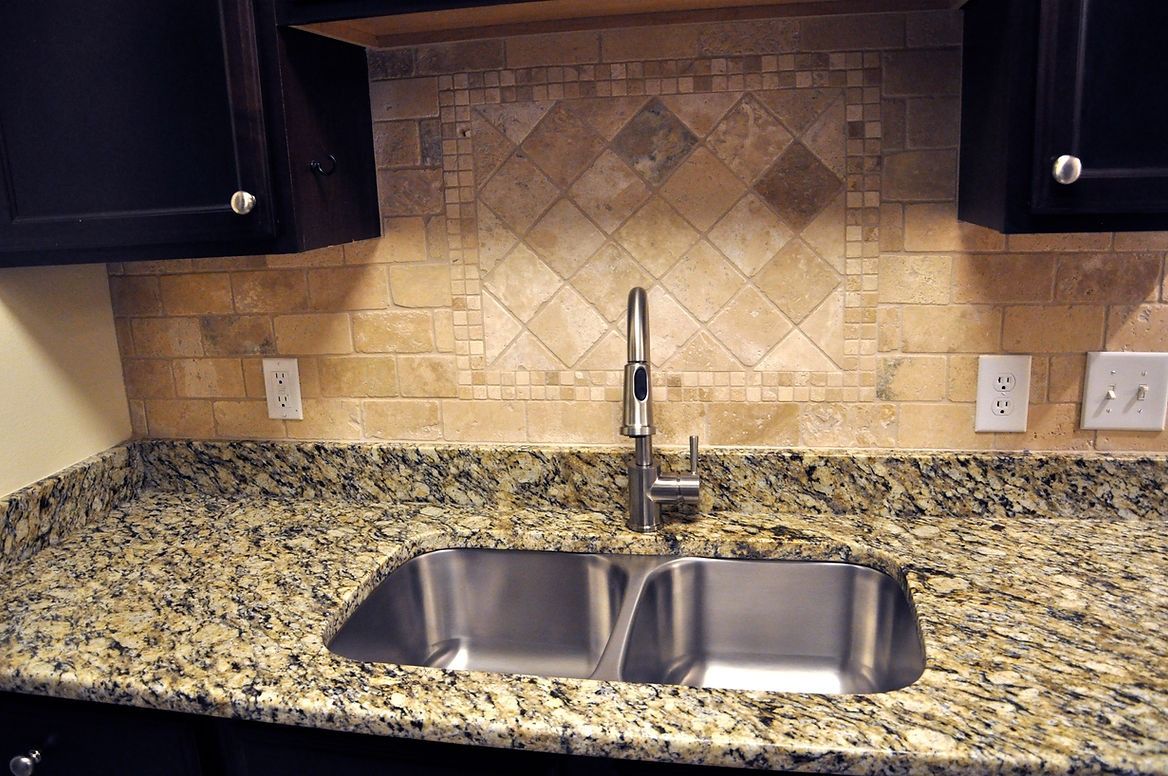 A kitchen with granite counter tops and a stainless steel sink