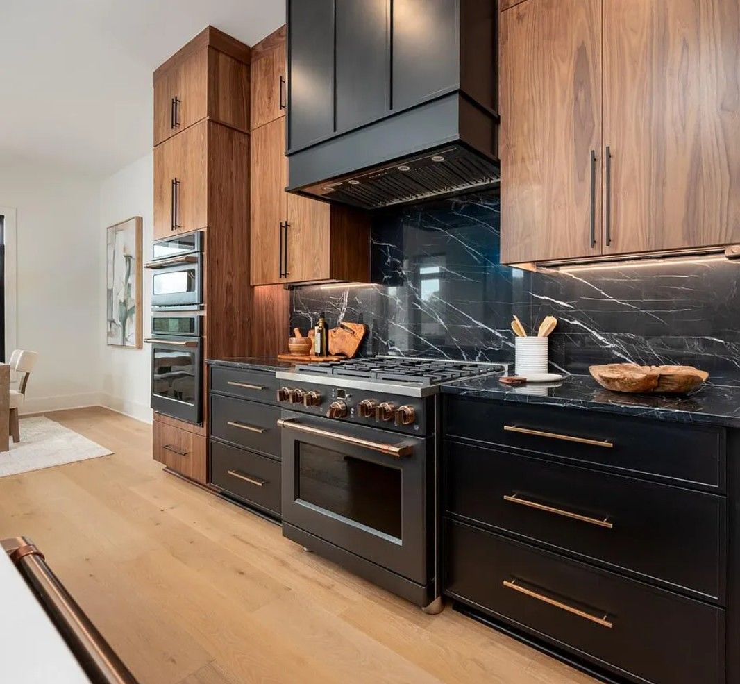 Modern kitchen with dark cabinetry, wooden accents, and a marble backsplash.
