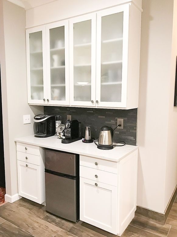 A kitchen with white cabinets , stainless steel appliances , and a refrigerator.