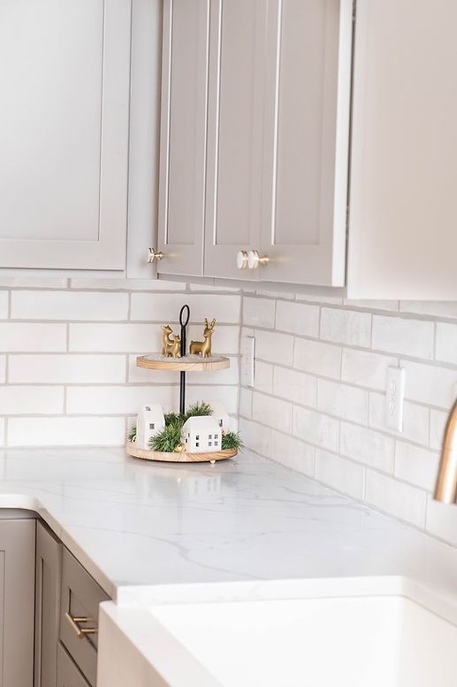 A kitchen with white cabinets , white subway tiles , a sink , and a tray on the counter.